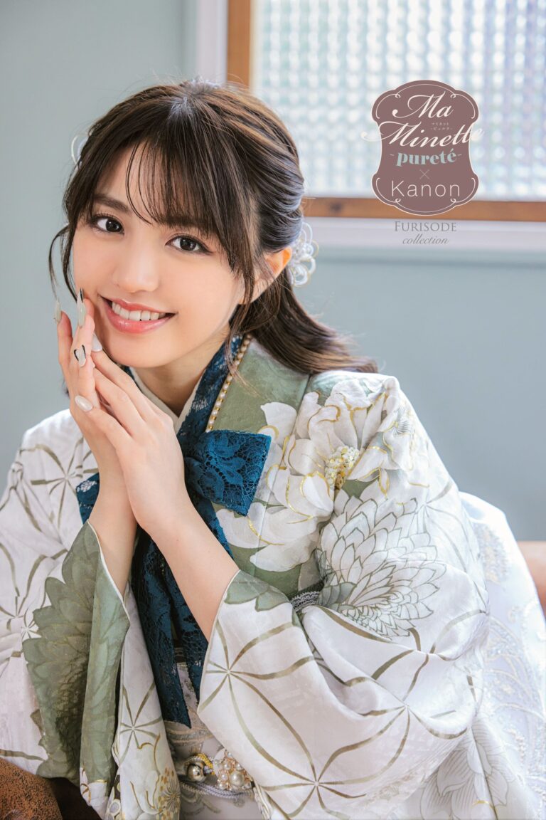 緑、青、白が混ざった花柄の着物を着た笑顔の女性。両手で優しく顔に触れ、窓の前に座っています。黒髪はヘアピンで留められています。窓には四角い模様があり、隅に文字が表示されています。