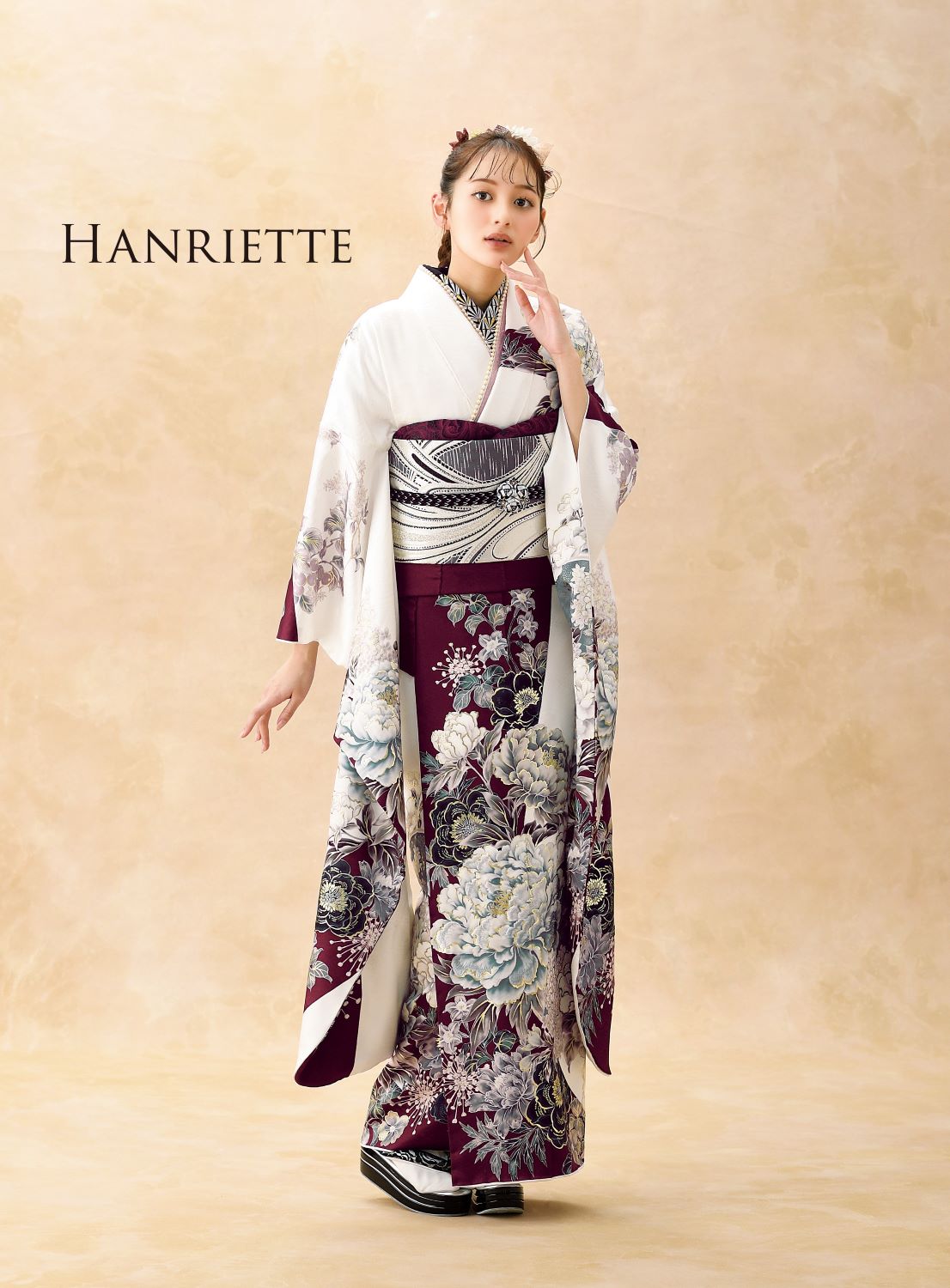 ワインレッドと白の配色で花柄が特徴的な日本の伝統的な着物を着た人物。ベージュの背景に立ち、花の髪飾りをつけています。画像の左上に「HANRIETTE」という文字があります。.