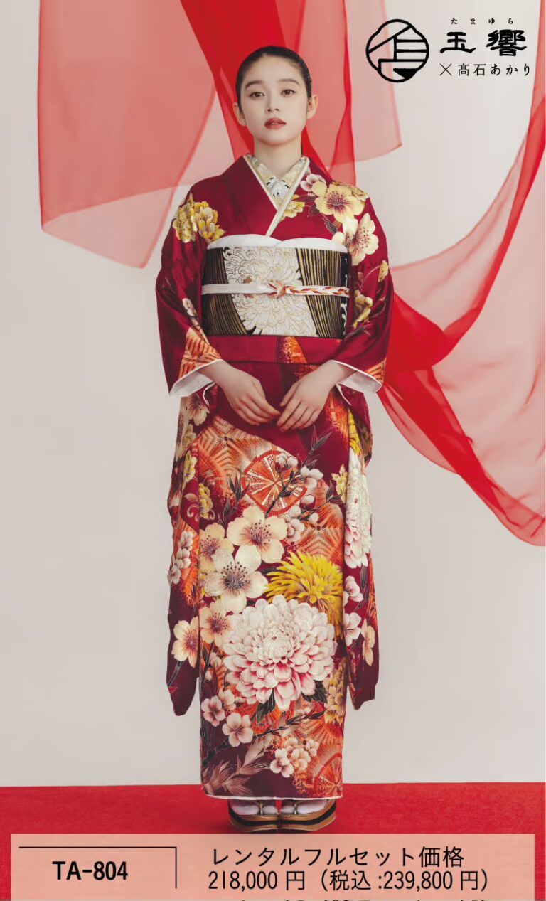 中央に、深紅の花柄の着物を着て、金と黒の帯を締めた若い女性が立っている。髪はきちんと後ろで結ばれ、唇は赤く、両手は体の横に下ろしている。彼女の背後には、淡い色の背景に赤い円形のアクセントが施されている。下部には日本語のテキストと価格が記載されている。.